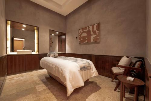 a bedroom with a bed and a mirror and a chair at Almare, a Luxury Collection Resort, Isla Mujeres, Adult All-Inclusive in Isla Mujeres