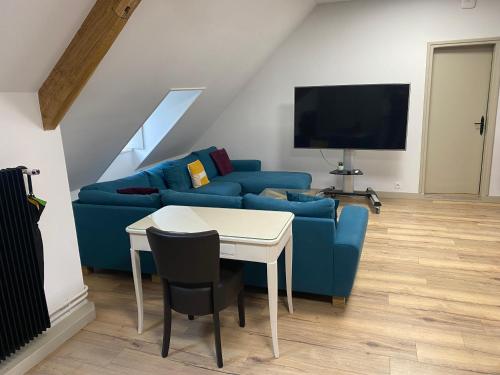 un salon avec un canapé bleu et une table dans l'établissement Appartement vintage - Terrasse - Fauteuils de cinéma, à Verton