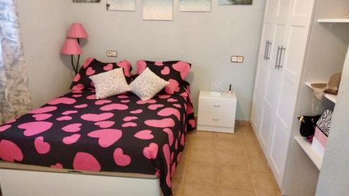 a bedroom with a black and pink bed with pillows at Villa di Esperanza in Comarruga