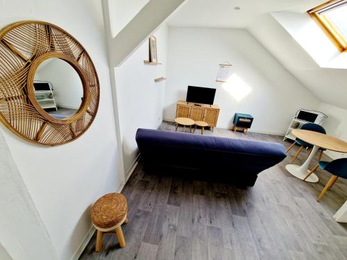 un salon avec un canapé bleu et un miroir dans l'établissement Les Studios Proche Gare d'Aulnoy-Aymeries, à Aulnoye-Aymeries