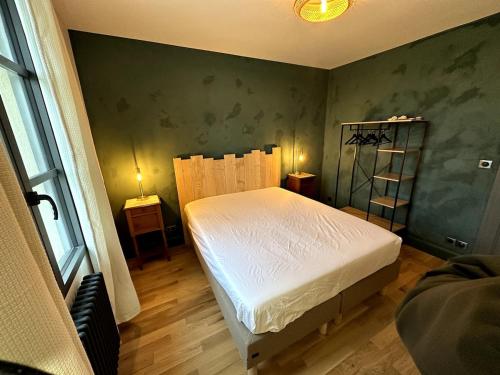 a bedroom with a white bed and a green wall at Appartement cosy N3 à 3 min de Giverny in Limetz