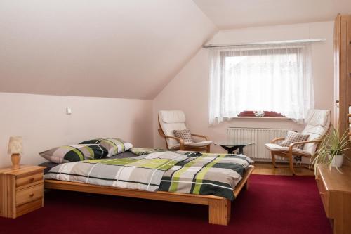 a bedroom with a bed and chairs and a window at Privatunterkunft "An der Hecke" in Neuss