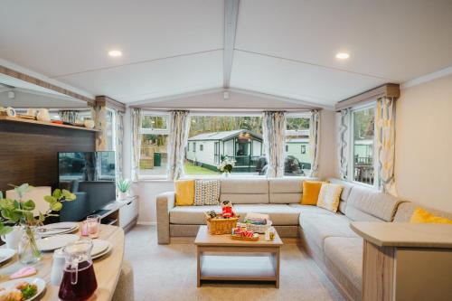 a living room with a couch and a table at Beautiful 3bed Caravan on Windermere - on White Cross Bay Holiday Park in Troutbeck Bridge