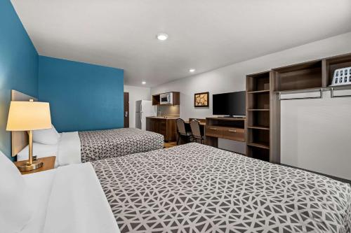 una camera d'albergo con due letti e una scrivania di WoodSpring Suites Loves Park - Rockford a Loves Park