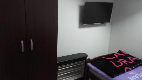 a bedroom with a bed and a dresser and a tv at Hostel IN Club in Zagreb