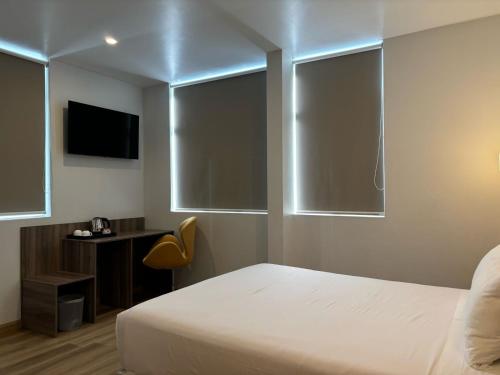 a bedroom with a bed and a desk with a television at HOTEL PIEDRA SANTA - Moquegua in Moquegua