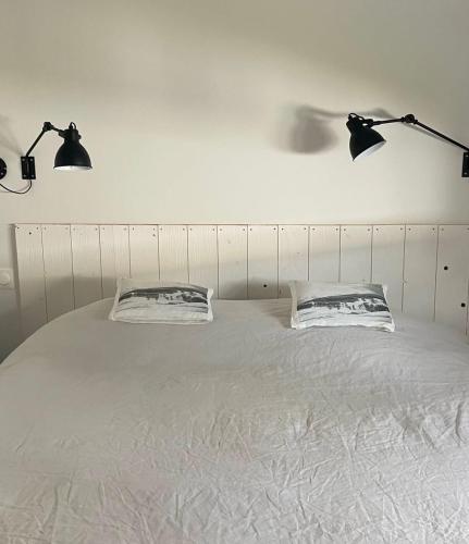 - un lit avec 2 oreillers et 2 lumières au-dessus dans l'établissement La planque en re, à Sainte-Marie de Ré