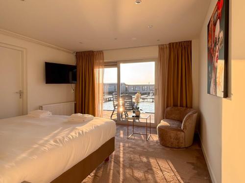 a hotel room with a bed and a chair and a balcony at VISSERSLUST Rooms, Apartments and Houseboats in Vinkeveen