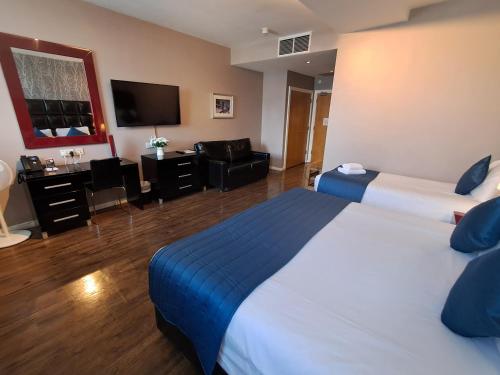 a hotel room with two beds and a flat screen tv at The Royal Hotel Cardiff in Cardiff