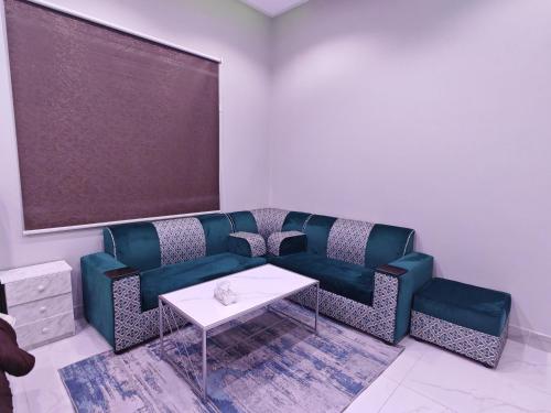 un soggiorno con un divano blu e un tavolo di Home1 2BR هوم1 شقة غرفتين بمدخل مستقل تبعد اقل من 5 كلم عن الحرم النبوي a Medina