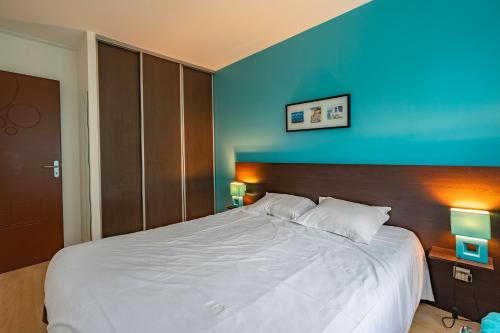 a bedroom with a large white bed with a blue wall at Ile d'Aix in Saint-Simon-de-Bordes