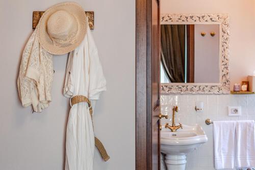 a bathroom with a sink and a hat hanging on the wall at Altalena Luxury Rooms and Spa in Siena
