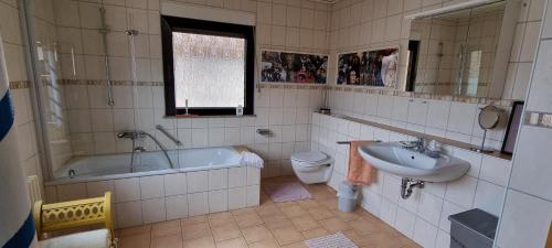 a bathroom with a tub and a sink and a toilet at Gästehaus Margerite in Blieskastel