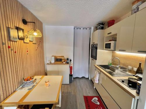 une petite cuisine avec une table et un réfrigérateur dans l'établissement Chaleureux studio Glovettes VILLARD DE LANS, à Villard-de-Lans