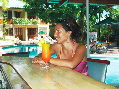 a woman sitting at a table with a drink at Hexagon International Hotel, Villas & Spa in Nadi