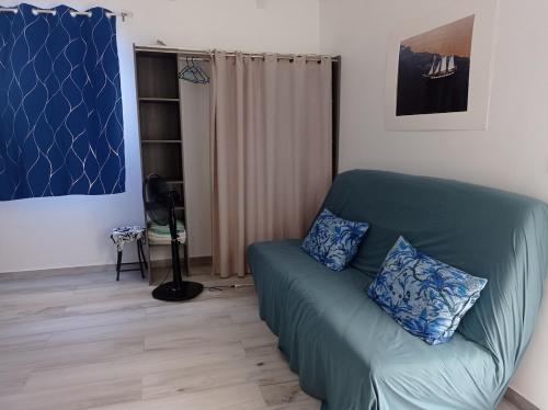 a living room with a green couch with blue pillows at Haut de villa indépendant, vue et accès mer, 100m de la plage, idéal famille in La Trinité