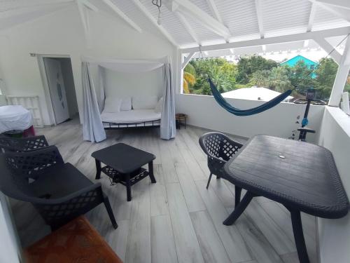 a room with a hammock and a table and chairs at Haut de villa indépendant, vue et accès mer, 100m de la plage, idéal famille in La Trinité