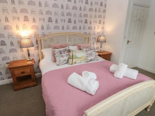a bedroom with a pink bed with towels on it at The Smithy in Chathill