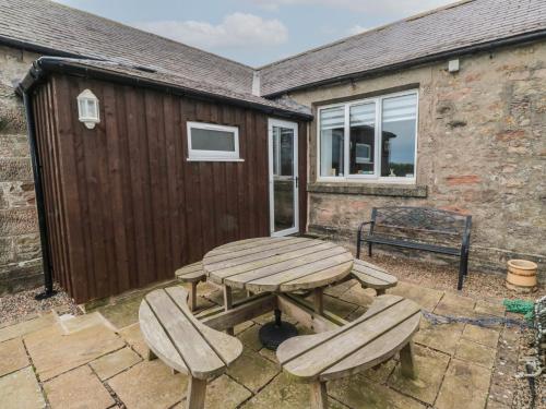 a picnic table and benches in the backyard of a house at The Smithy in Chathill