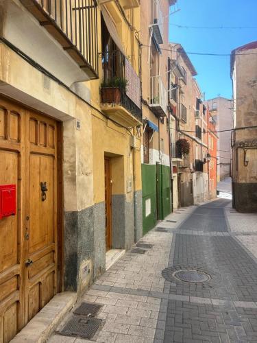 an empty alley with a wooden door and buildings at La guarida rústica del zorro in Jijona