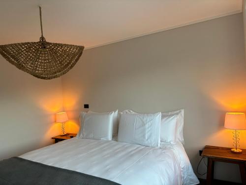 a bedroom with a white bed with two lamps at The Roses in Puerto Varas