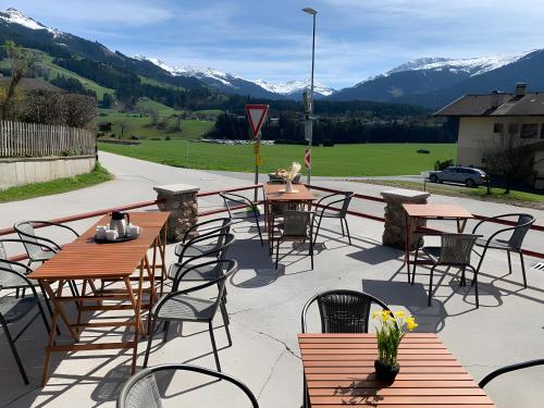 a patio with tables and chairs with mountains in the background at Feichtenhäusl app 2 in Westendorf