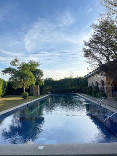 a large pool of water with a house in the background at Cute 2 room House with pool access in Tarlac