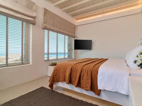 a bedroom with a bed and a flat screen tv at Mykonos Rocks Villas & Suites in Mýkonos City