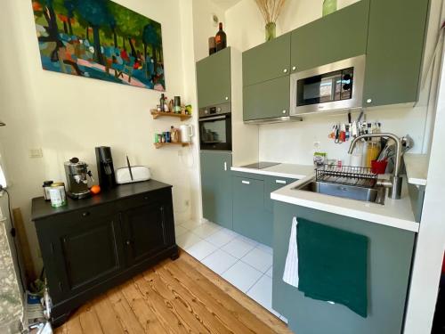 une cuisine avec des armoires vertes et un évier dans l'établissement Appt XVIII centre historique rue du Cloître, à Bordeaux
