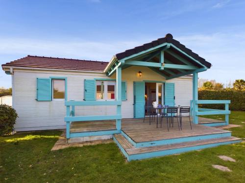 una casa con terraza con mesa y sillas en Chalet pour 4 dans une résidence avec piscine, en Pont-lʼAbbé