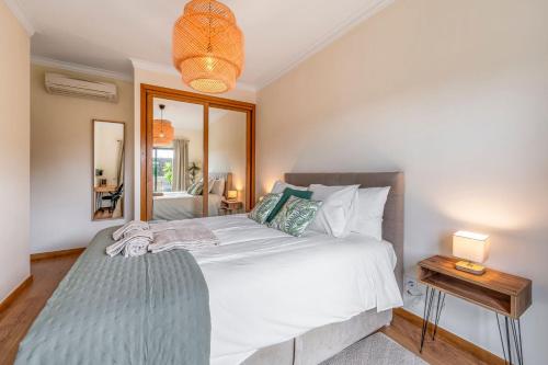 a bedroom with a large white bed and a mirror at Serenity Costa da Caparica in Almada