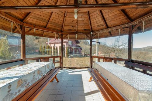 an empty porch with benches and a wooden roof at Casa Cristiana in Bologa