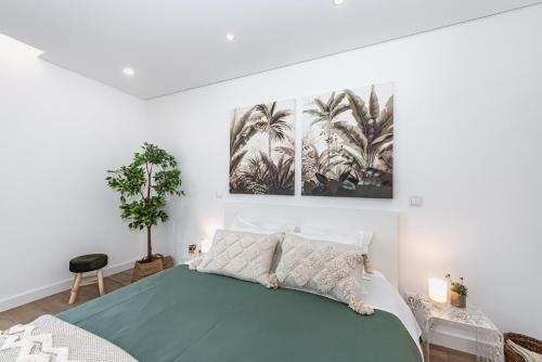 a bedroom with a bed with a green blanket and palm trees at Casa da Oliveira ~ Azeitão in Azeitao