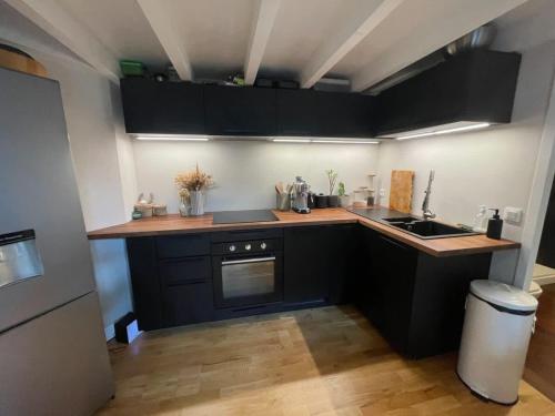 - une petite cuisine avec des placards noirs et un évier dans l'établissement Loft de Charme au Cœur du Centre Historique, à Bordeaux