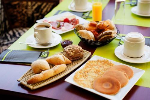 a table topped with plates of pastries and cups of coffee at Hôtel Marso in Amnéville