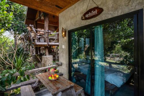 a patio with a table and a glass door at คอร์เดียร์ บ้านไร่ริมธารโฮมสเตย์ แก่งกระจาน in Ban Wang Malako
