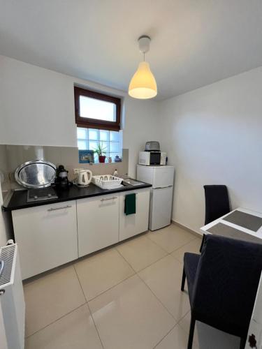 a small kitchen with white cabinets and a window at Mandula Apartman in Cegléd
