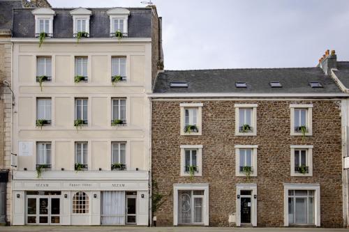 duży ceglany budynek z roślinami na oknach w obiekcie Sézam-Appart-Hôtel w Saint-Malo
