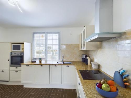 - une cuisine avec des placards blancs et un bol de fruits sur le comptoir dans l'établissement Authentique maison bretonne pour 6 à Plovan, à Plovan