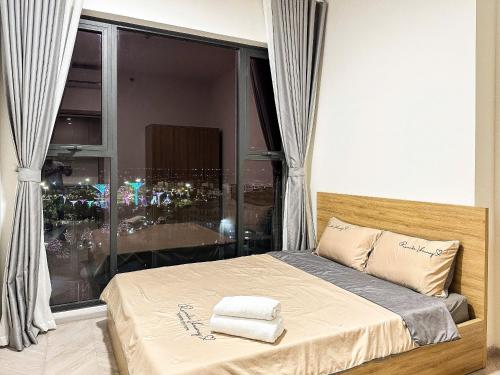 a bedroom with a bed and a large window at Honeymoon homes - Vinhomes Grand Park Quận 9 - 2 phòng ngủ in Gò Công