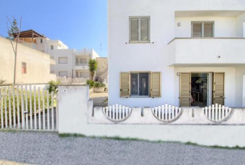 a white house with a fence in front of it at Casa vacanze torre vado in Marina di Pescoluse