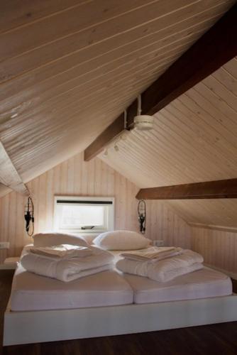 two white beds in a room with a wooden ceiling at Sisters Beachbungalows in Katwijk aan Zee