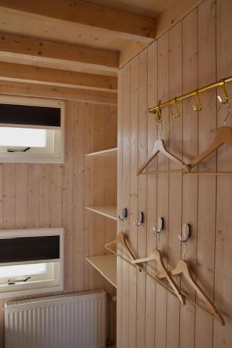 a room with wooden walls with shelves and a window at Sisters Beachbungalows in Katwijk aan Zee