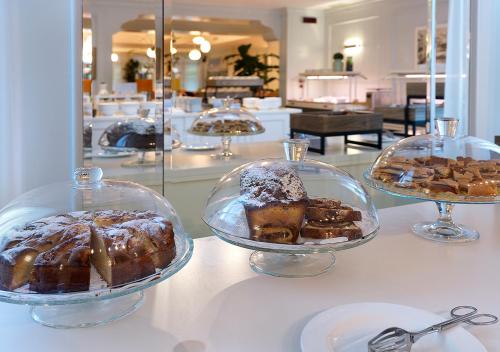 three cakes and pastries in glass dishes on a counter at Iseo Lago Hotel in Iseo
