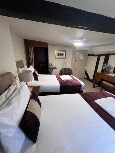 a hotel room with two beds and a desk at The Talbot Hotel in Ledbury