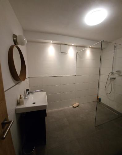 a bathroom with a shower and a sink and a mirror at Modernes Apartment in Gondelsheim