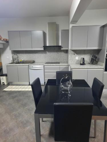 a kitchen with a black table and white cabinets at Rose Sun House in Ponta do Sol