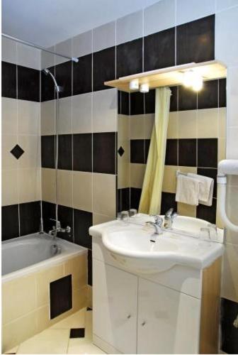a bathroom with a sink and a bath tub at Hôtel de l'Aveyron in Paris