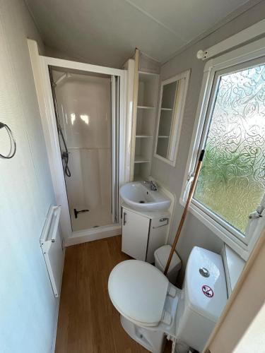 une petite salle de bain avec toilettes et lavabo dans l'établissement Mobil Home, 4 places 2 chambres, camping 4 étoiles, Bretagne, sud Finistère, à Clohars-Carnoët