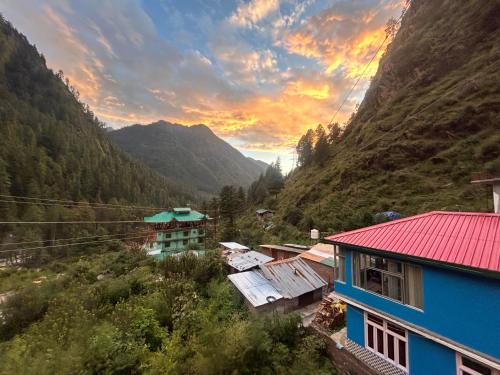 a group of houses in a valley with mountains at Formosa cafe & hostel in Kasol